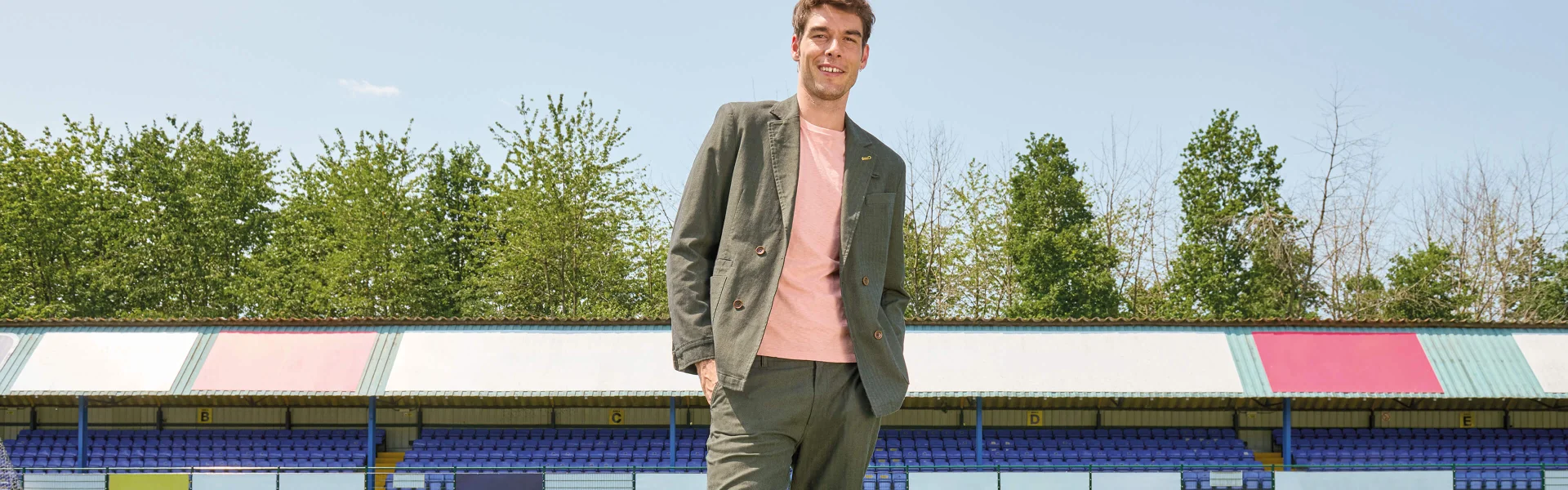 Mann in passender grüner Jacke und Hose mit pinkfarbenem Oberteil