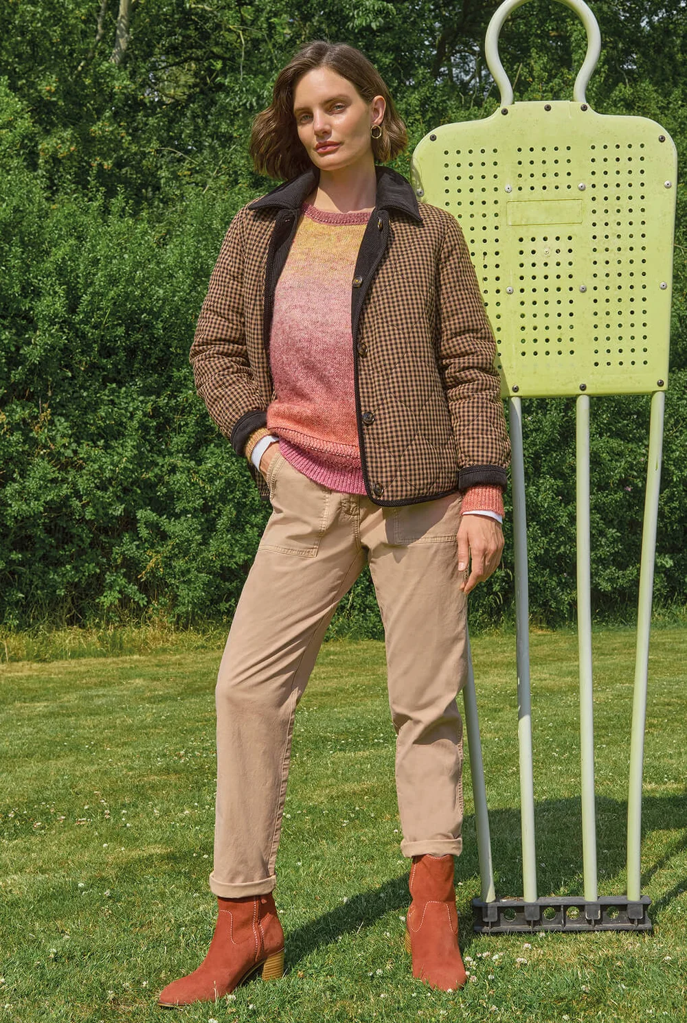 Frau in olivgrüner Jacke, beigefarbenen Hosen und bunten Stiefeln