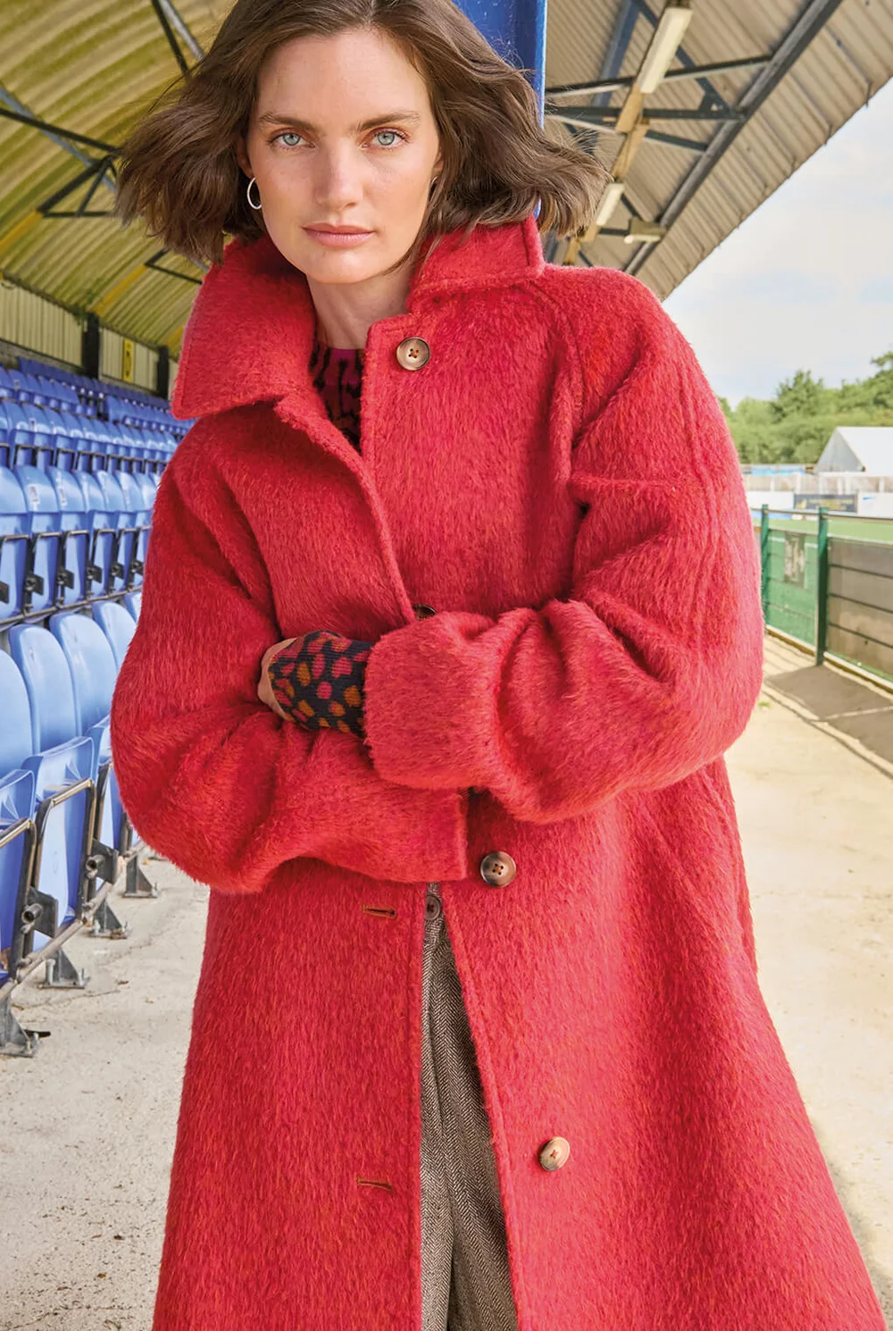 Frau mit verschränkten Armen in leuchtend rotem Mantel